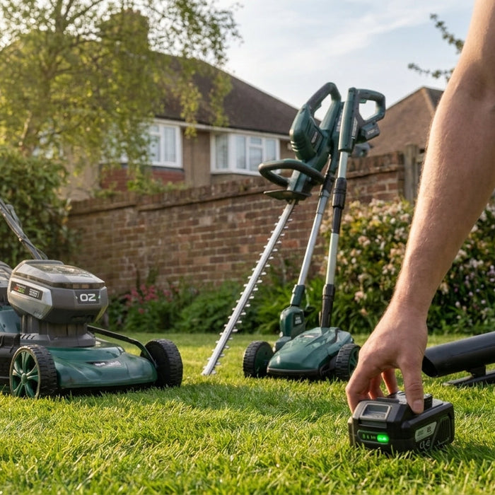Spectrum 40V cordless garden tool kit laid out on a lawn with the shared lithium-ion battery centred